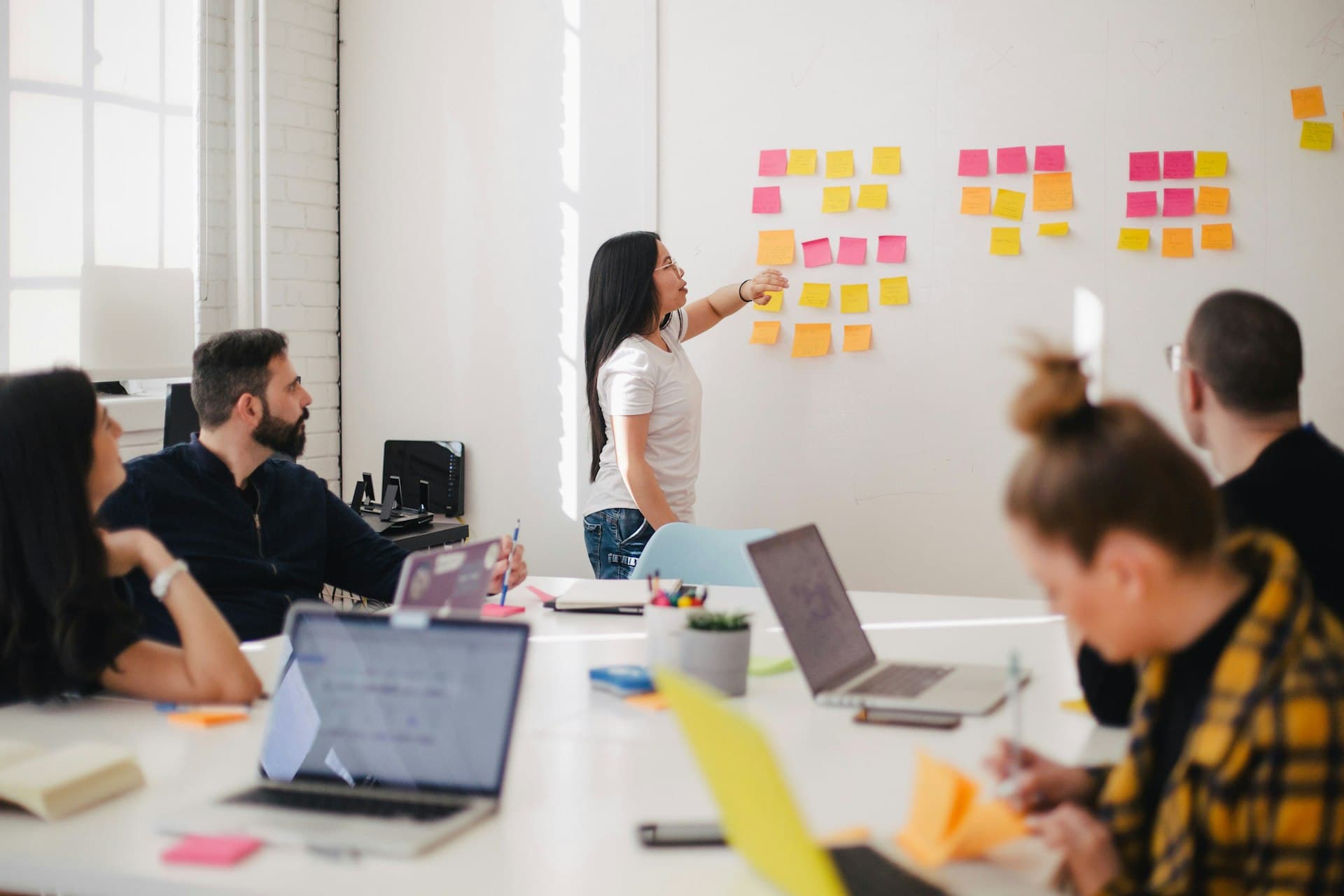 Team planning a project around sticky notes on a whiteboard